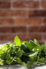 Bunch of peppermint on a table on a sunny day. Brown brick wall background
