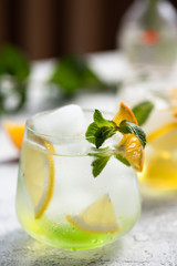 Refreshing lemonade with peppermint, oranges and lemons on a table on sunny day. Close-up view
