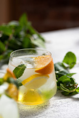 Refreshing lemonade with peppermint, lemon and orange. Sprigs of mint on a table. Close-up view