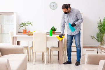 Young male contractor cleaning the house in coronavirus concept