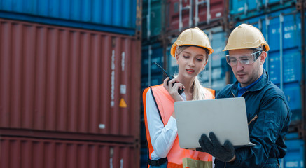 Technician or engineer with yellow helmet use walkie-talkie to contact with co-worker in cargo...