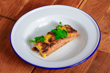 Homemade meat casserole with mushrooms and tomatoes and fresh pardley served on white plate over wooden background.