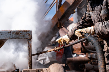 Worker use high pressure steam jet to cleaning splashing the dirt of tube bundle in industrial...
