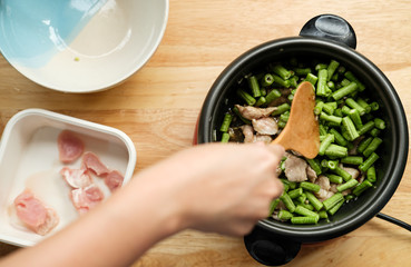 Unrecognized woman hand cooking Thai food with green yardlong bean and meat pork on the top angle shot