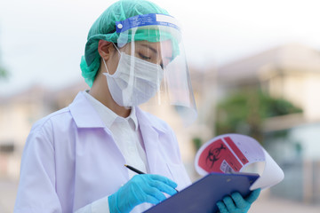 Woman doctor, holding patient report form folder, outdoor portrait, Coronavirus COVID-19 pandemic. (Fake QR Code and Barcode)