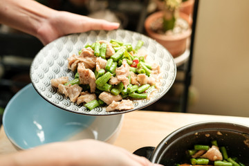 Woman hand cooking Thai food with yardlong bean and pork meat on the wooden table close up view angle