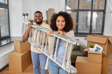 moving, people, repair and real estate concept - happy african american couple with ladder at new...