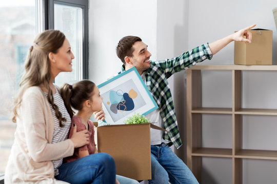 mortgage, family and real estate concept - happy mother, father and little daughter with stuff in boxes moving to new home