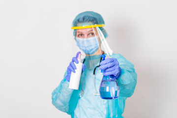 Woman wearing gloves, biohazard protective suit, face shield and mask with hand sanitizer bottle and disinfection gel. corona virus or Covid-19 protection.