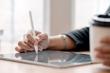 Closeup view woman hand using digital pen writing or drawing on tablet screen, copy space.