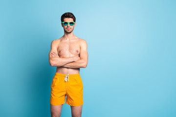 Portrait of his he nice attractive content virile masculine muscular guy wearing swimming shorts folded arms isolated over bright vivid shine vibrant green blue turquoise color background