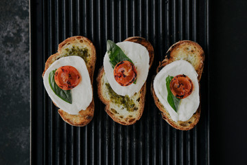 Italian traditional bruschetta with tomato, mozzarella cheese and pesto sauce. Grilled caprese sandwich