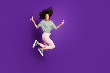 Full body photo of crazy funny afro american girl jump make v-sign scream feel rejoice wear striped shirt pink outfit isolated over violet color background