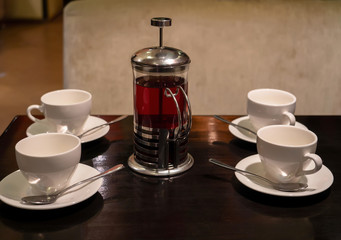 four empty tea cups and a French press are on a wooden table in the cafe. top view