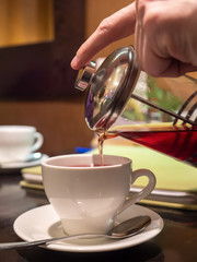 a man  pours tea into a Cup from a French press teapot. close up. copy space