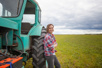 young attractive girl woman working in a field on a tractor, rural profession for young people,...