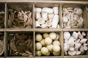 Small white decorative products (buttons, beads) of different shapes of wood in different departments closeup