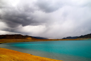 Plateau holy lake, blue-green lake water, coffee-colored distant mountains, rising water vapor and clouds