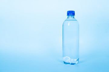 Naklejka premium plastic bottle of mineral water on a clear blue background with copy space