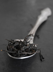 tea leaves in a spoon on a black board
