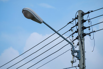Close up street lamp hanging on electric pole isolated on blue clouds sky background. Electric pole...