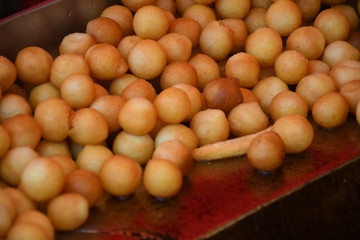 A lot of small round deep fried donuts, simple, no syrup or dipping sauce. Large bowl of donuts