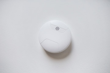 fire alarm system, safety and security concept - domestic smoke detector or sensor on white ceiling