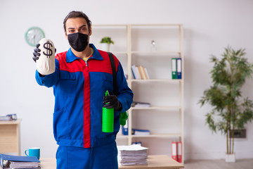 Young male contractor disinfecting office