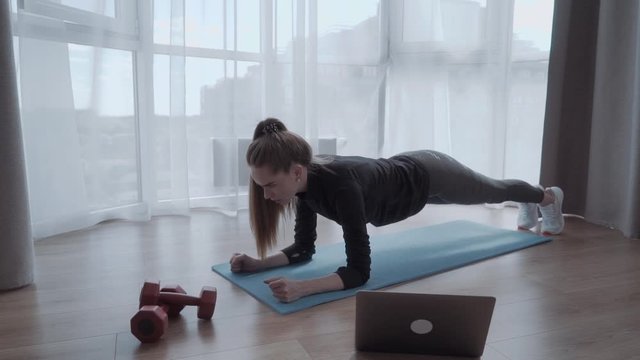 Video lesson. Nice young woman looking at the laptop screen while watching a workout tutorial