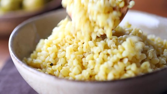 Macro footage of ceramic bowl with freshly brewed bulgur. Healthy nutrition, vitamin cereals.