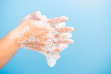 Fototapeta premium Closeup body care Asian young woman washing hands with soap have foam, hygiene prevention COVID-19 or coronavirus protection concept, isolated on blue background