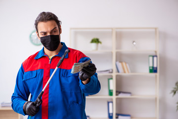 Young male contractor disinfecting office