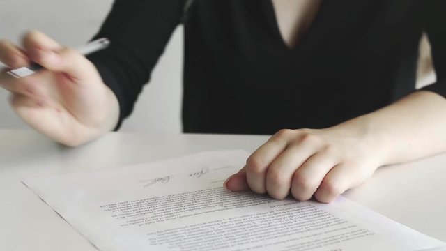 Businesswoman is signing cooperation agreement. Person heand signs the document