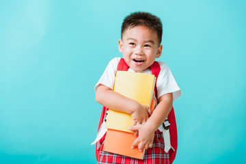 Back to school concept. Portrait Asian happy funny cute little child boy smiling and laugh hug books, studio shot isolated blue background. Kid from preschool kindergarten with school bag education