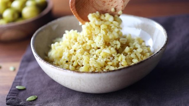 Macro footage of ceramic bowl with freshly brewed bulgur. Healthy nutrition, vitamin cereals.