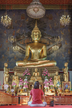 prayer prays to giant golden buddha inside thai Wat Ratchanatdaram Temple in Bangkok Thailand