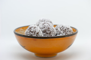 Coconut balls in an orange bowl on white background