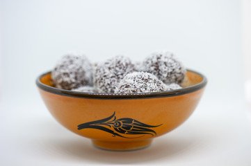 Coconut balls in an orange bowl on white background