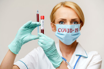 medical doctor nurse woman wearing protective mask and gloves - holding virus blood test tube and syringe