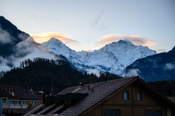 Swiss apls in morning with cloud cover, Eiger, Monch and Jungfrau with red summit peaks reflecting...