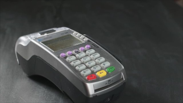 The user makes payment by credit card. Swipe to the terminal of non-cash payment. Man hand with credit card swipe through pos terminal. Banking services of electronic money, making transaction
