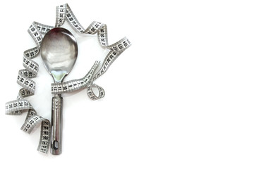 measuring tape and iron spoon isolated on a white background. Copy space. The concept of weight loss or diet.