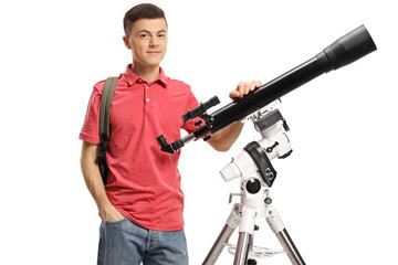 Male student standing next to a telescope and looking at the camera