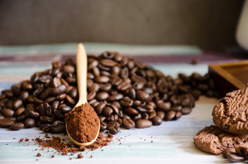 Closeup coffee beans and grinded powder on a wooden spoon