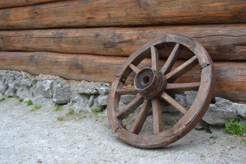 Obraz premium Vintage wheel from the cart on the background of a log wall