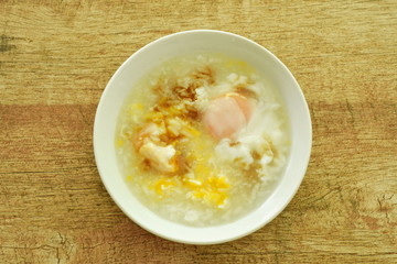 rice porridge with egg yolk dressing sot sauce on bowl