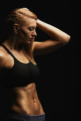 Fototapeta na wymiar Fitness fashion concept. Beautiful girl with a perfect sports figure posing on camera. ideal abdominal muscles, sports torso. On a dark background. Copy space