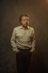 Fototapeta premium Cool fashionable middle aged man in khaki shirt and brown pants. Low key studio shot.