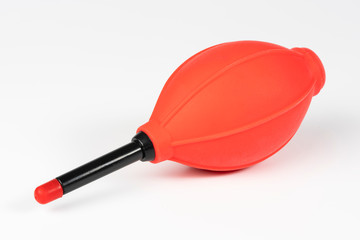 Red and black camera air blower for clearing dust particles from lens.