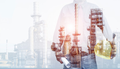 Double exposure of Engineer starnding with safety helmet, drawing plan, design with oil refinery industry plant background.